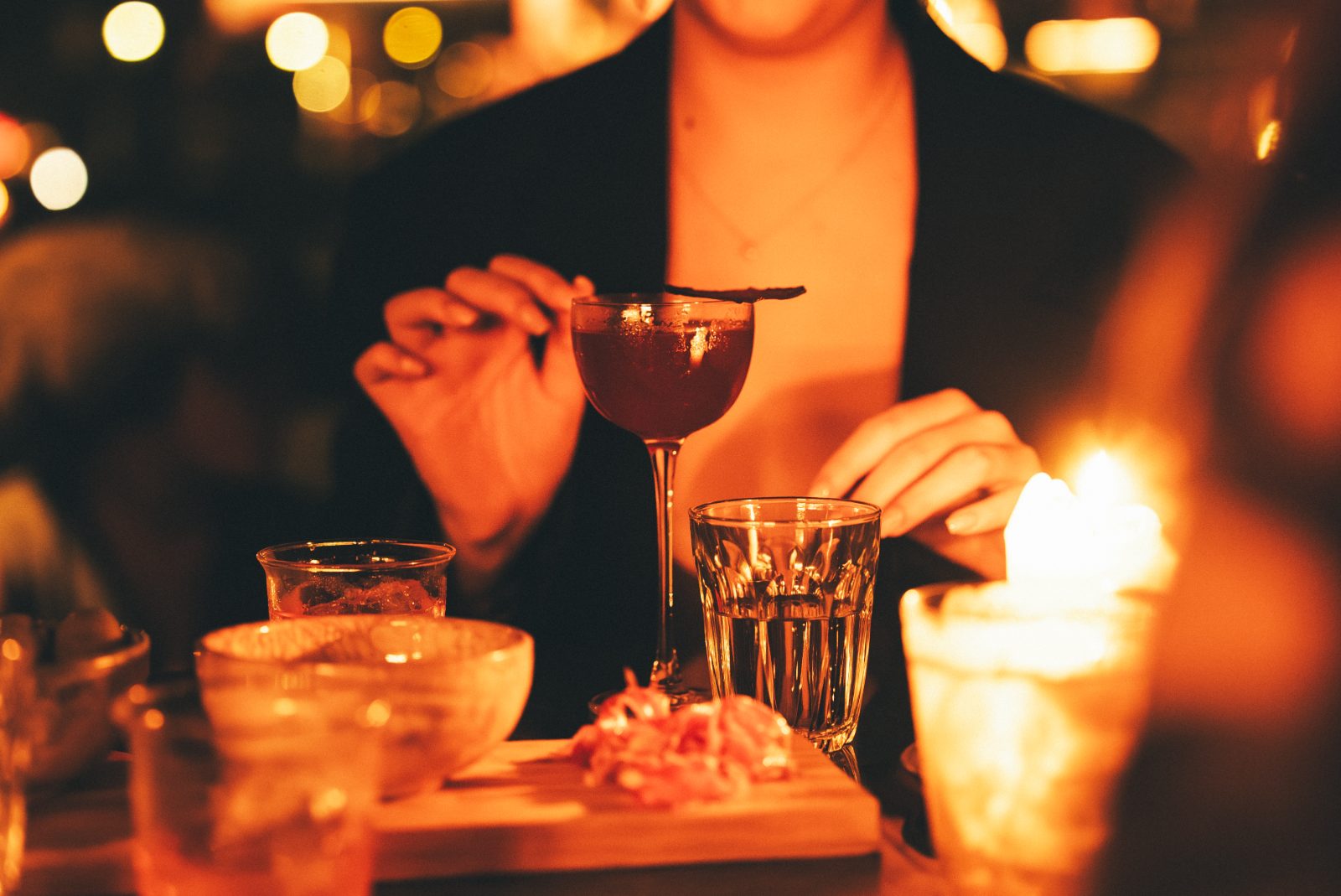 Gast roert in een cocktail bij kaarslicht